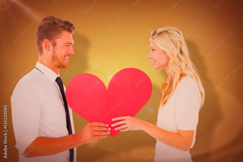 Composite image of attractive young couple holding red heart Composite image of attractive young couple holding red heart