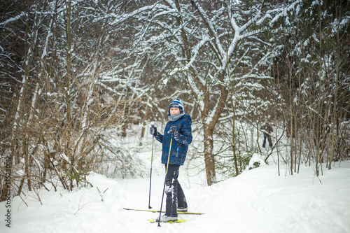 young boy with ski in the snow forest.
