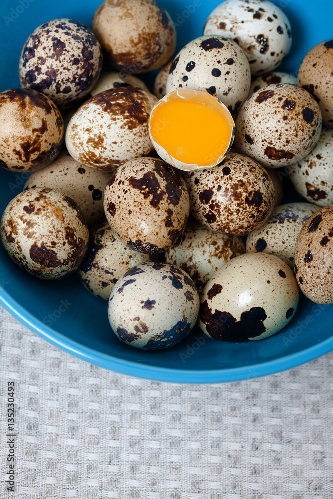 Fototapeta premium Quail eggs yolk in bowl wooden spoon and beige towel