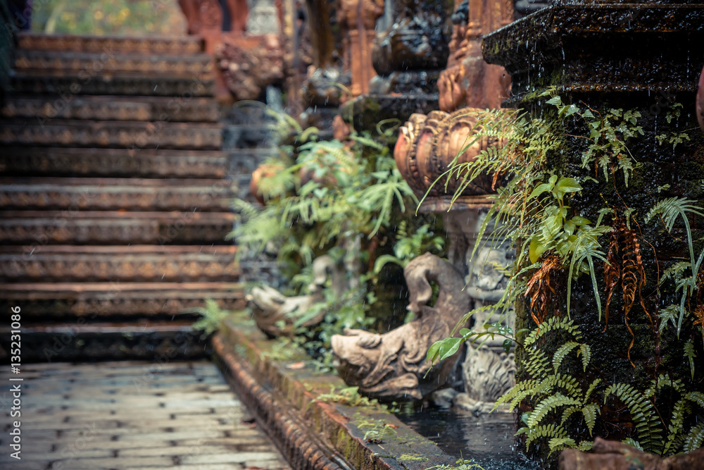 Ancient Asian style garden alley with old column overgrown with tropical plants and blurred background Ancient Asian style garden alley with old column overgrown with tropical plants and blurred background