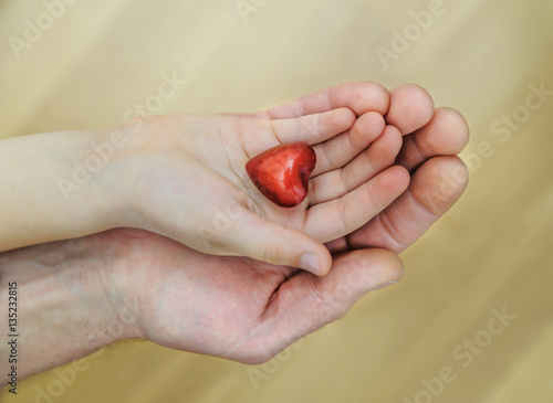 The small red heart is in the child's hand.