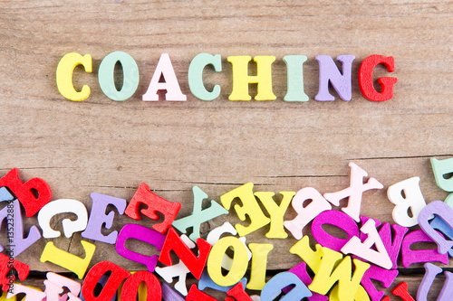 Text "Coaching" of colored wooden letters on a wooden background