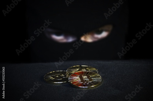Shiny gold bitcoin coin and masked man face on background