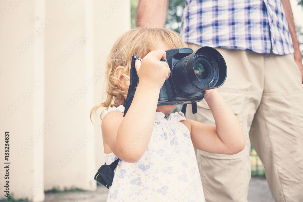 Little girl holding a camera and taking pictures. - obrazy, fototapety, plakaty 