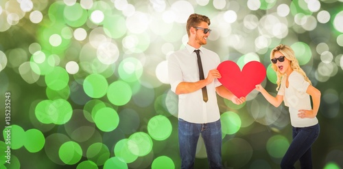 Composite image of cool young couple holding red heart