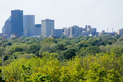 Green trees in spring spread out in front of the Rochester  New York skyline in afternoon light