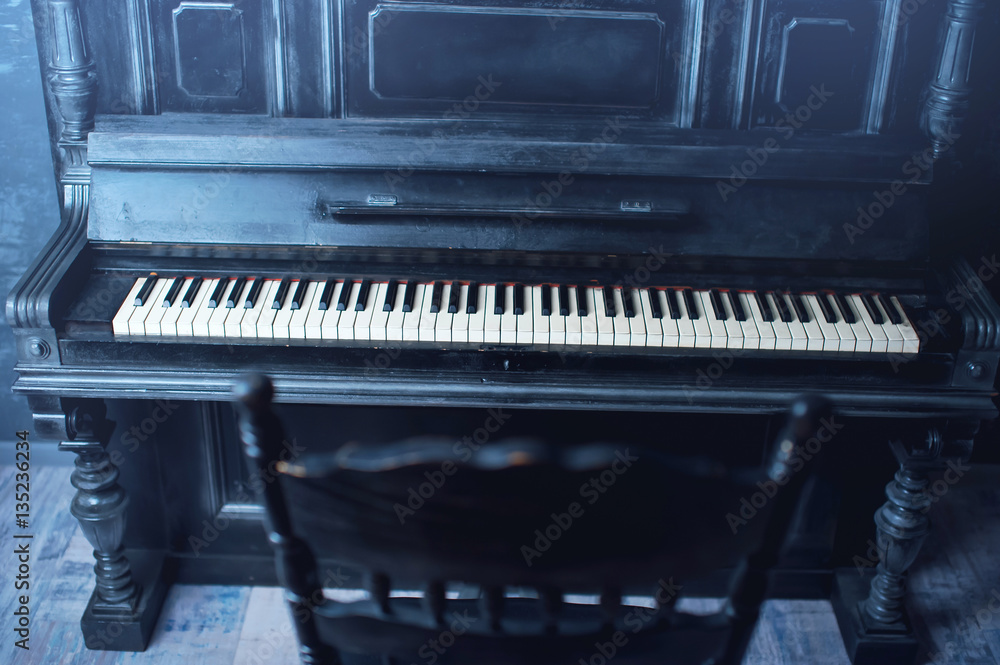Black antique piano and a chair. General form