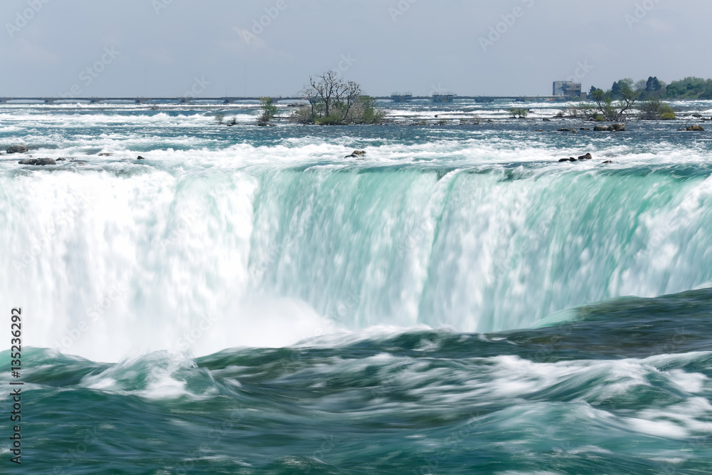 The bright blue water of Niagara Falls flows down the river and over the waterfall in spring