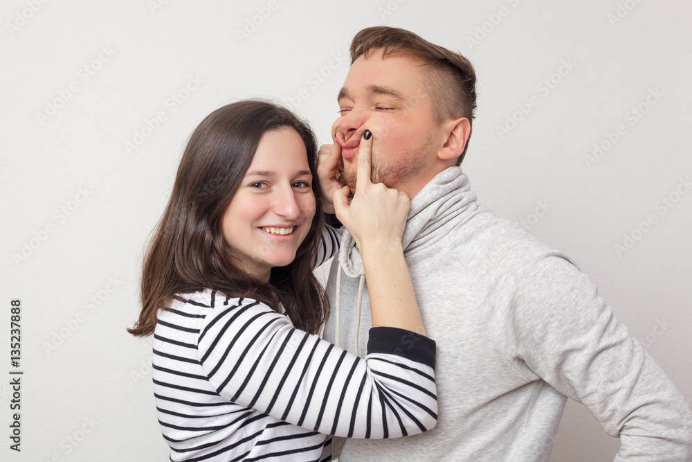 Beautiful girl tries to cheer her boyfriend. Pulls a smile on face Beautiful girl tries to cheer her boyfriend. Pulls a smile on face