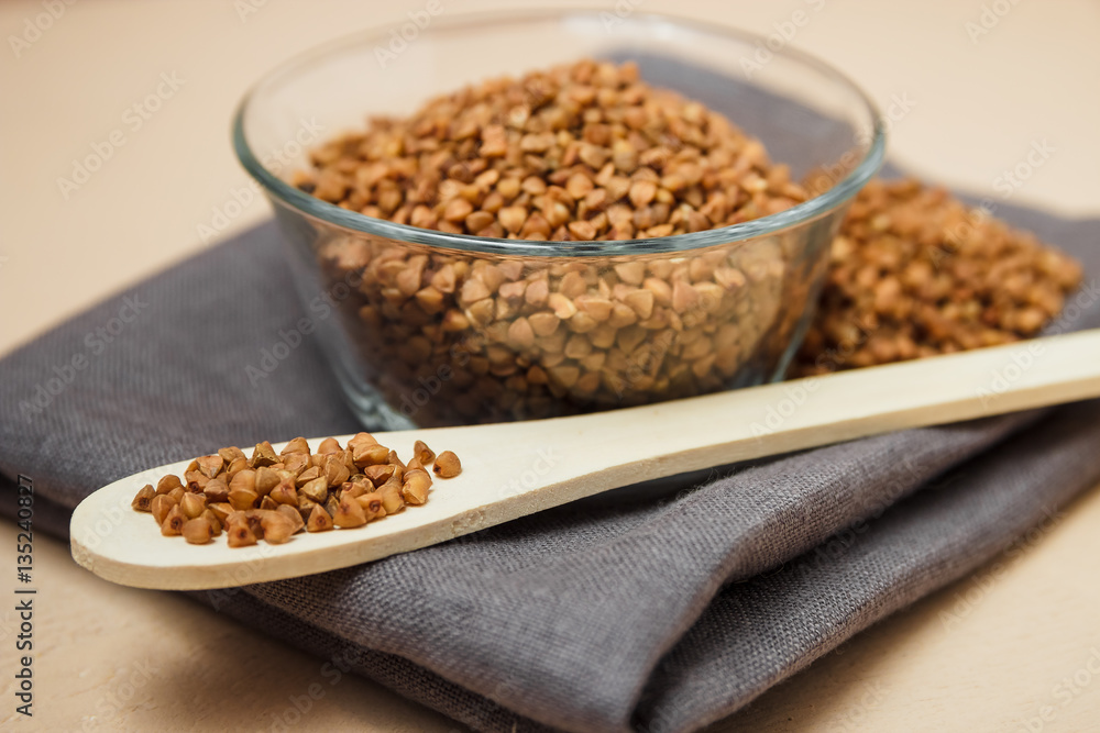 Buckwheat groats in bowl and wooden spoon Buckwheat groats in bowl and wooden spoon