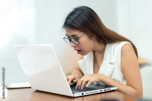 Busy Asian girl using laptop in office