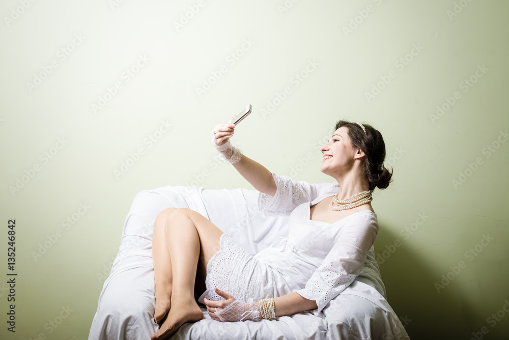 Happy joyful woman using mobile phone on light chair background Happy joyful woman using mobile phone on light chair background