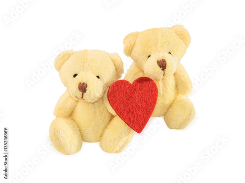 Two teddy bears sitting with red felt heart on white.