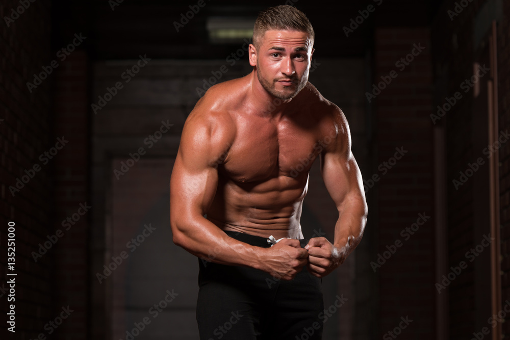 Muscular Man Flexing Muscles In Gym