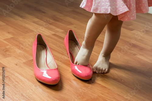 Baby girl wearing her mother's shoes