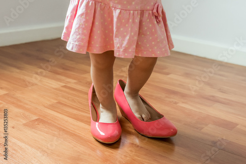 Baby girl wearing her mother's shoes