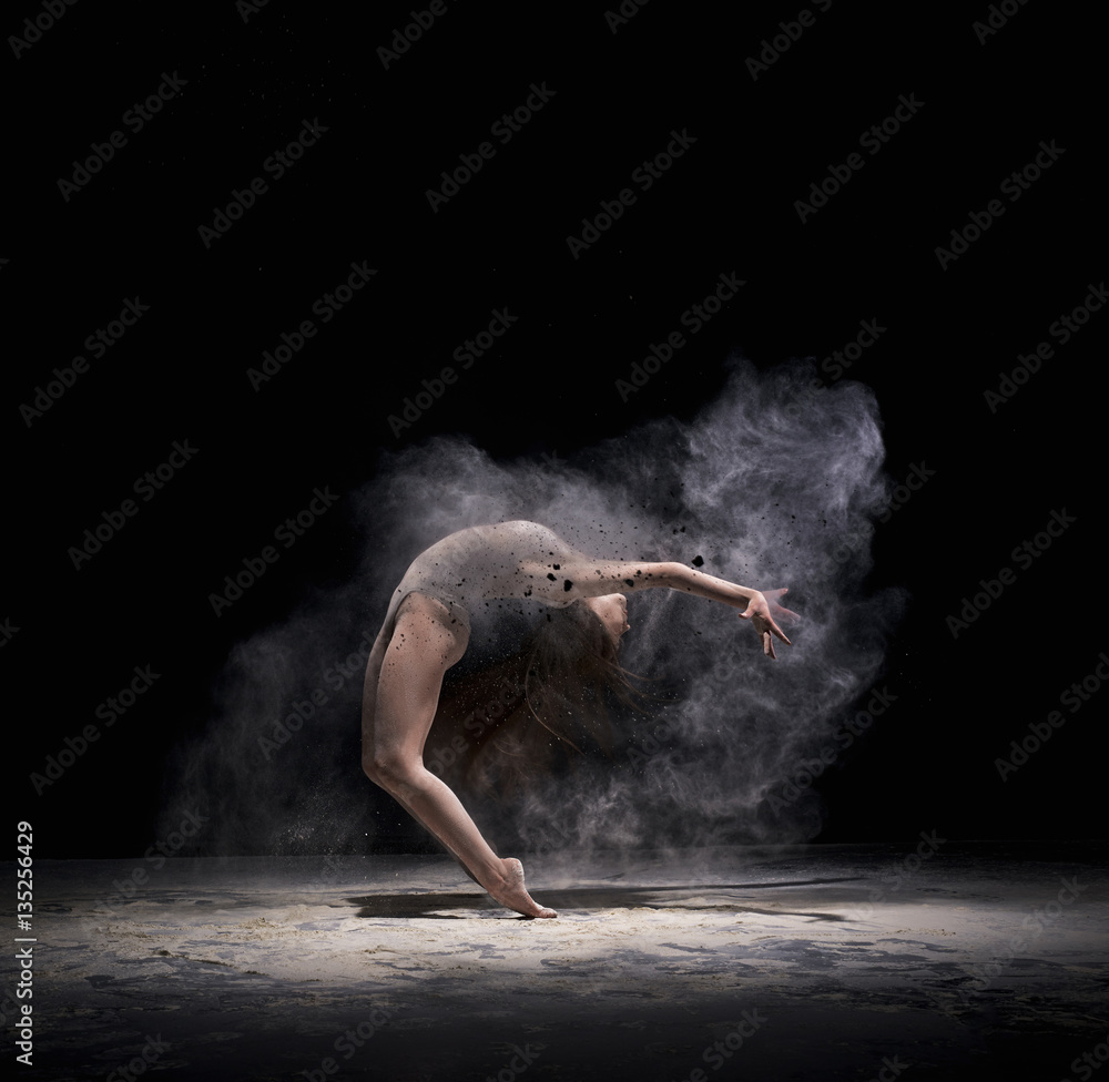 Graceful woman dancing in cloud of white dust