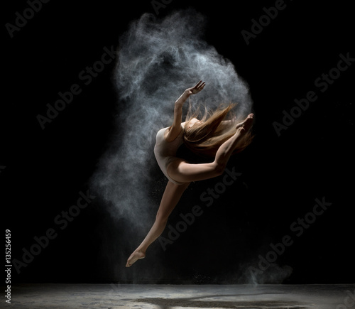 Graceful girl dancing in white dust powder
