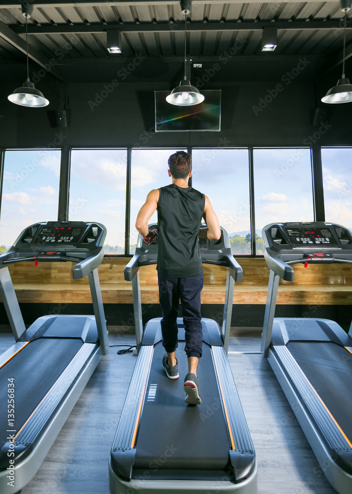 custom made wallpaper toronto digitalBack view of young man athlete with running on treadmill in gym.