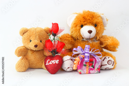 Two brown teddy bear with a red rose and a gift box on a white background.