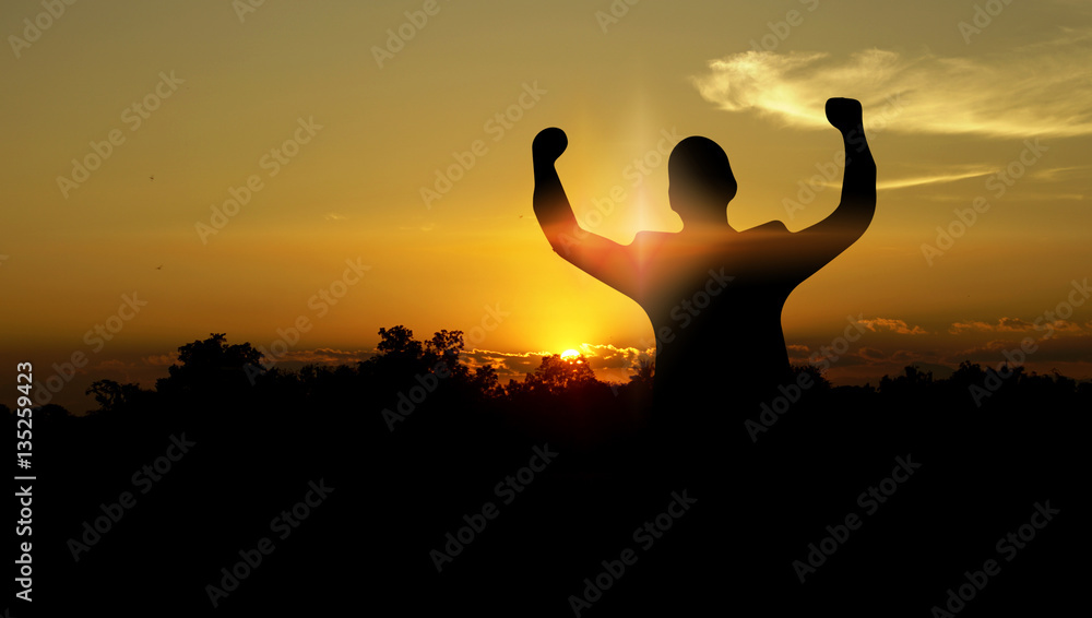 Silhouette of businessman raising arms in sunset. Business succe