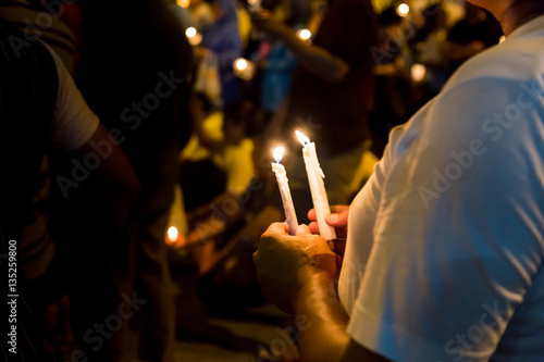 People holding candle vigil in darkness seeking hope, worship, prayer
