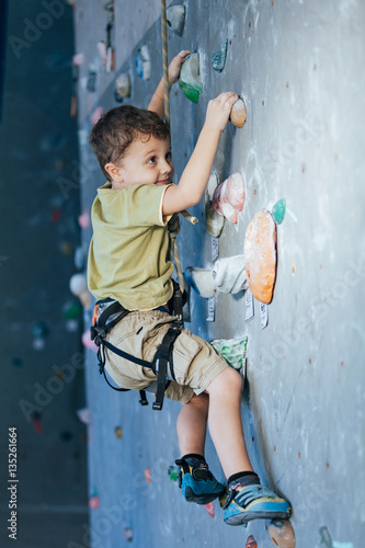 little boy climbing a rock wall indoor