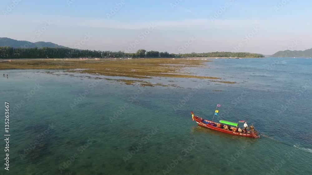 Traditional thai long-tail boat sailing in blue sea in low tide. HD aerial shot. Phuket, Thailand. Traditional thai long-tail boat sailing in blue sea in low tide. HD aerial shot. Phuket, Thailand.
