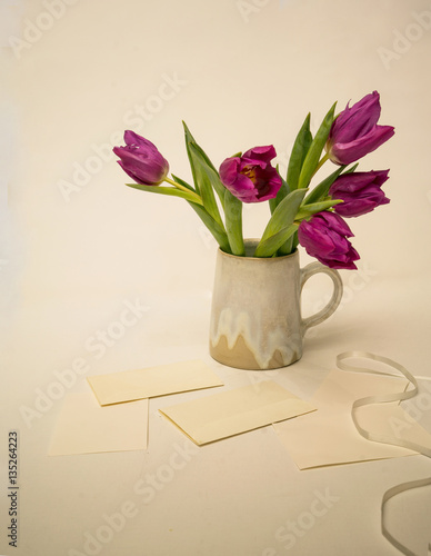 Fototapeta Naklejka Na Ścianę i Meble -  Pink tulips in a ceramic vase on a table with letters and envelopes