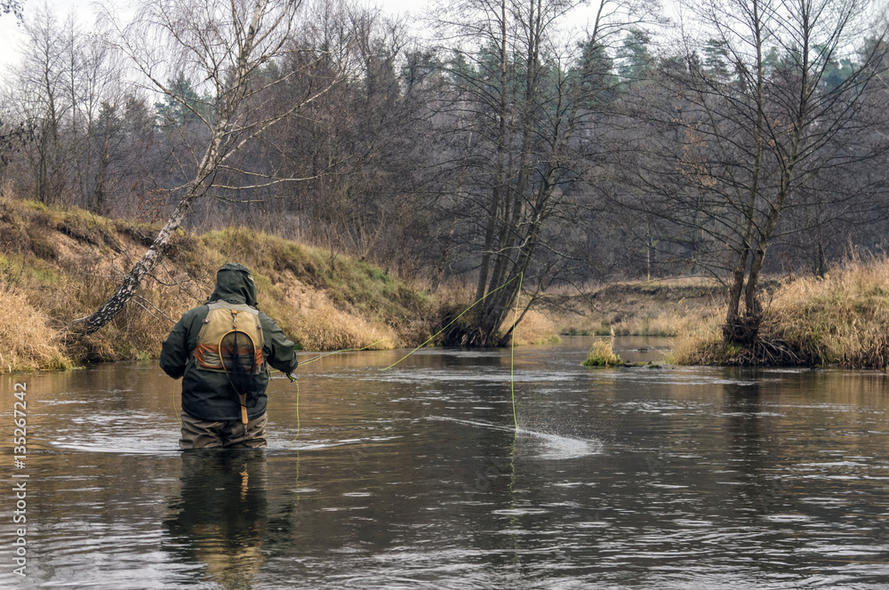 Fisherman fishing on a small spring river. Fly fishing. Fisherman fishing on a small spring river. Fly fishing.