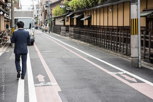 Wallpaper Mural In the picture we can clearly see that a man is walking on the street and infornt of him there is a truck parked by the side of the road few bushes are also vissible on the roof of the buildings. Torontodigital.ca
