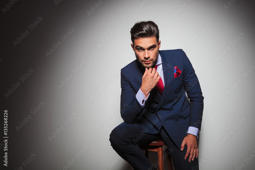 young gentleman is thinking while sitting on a stool young gentleman is thinking while sitting on a stool