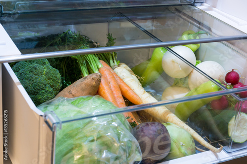 Open fridge , drawer filled with fresh vegetables