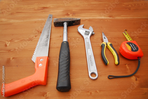 tools hammer screwdriver saw tape measure on a wooden background