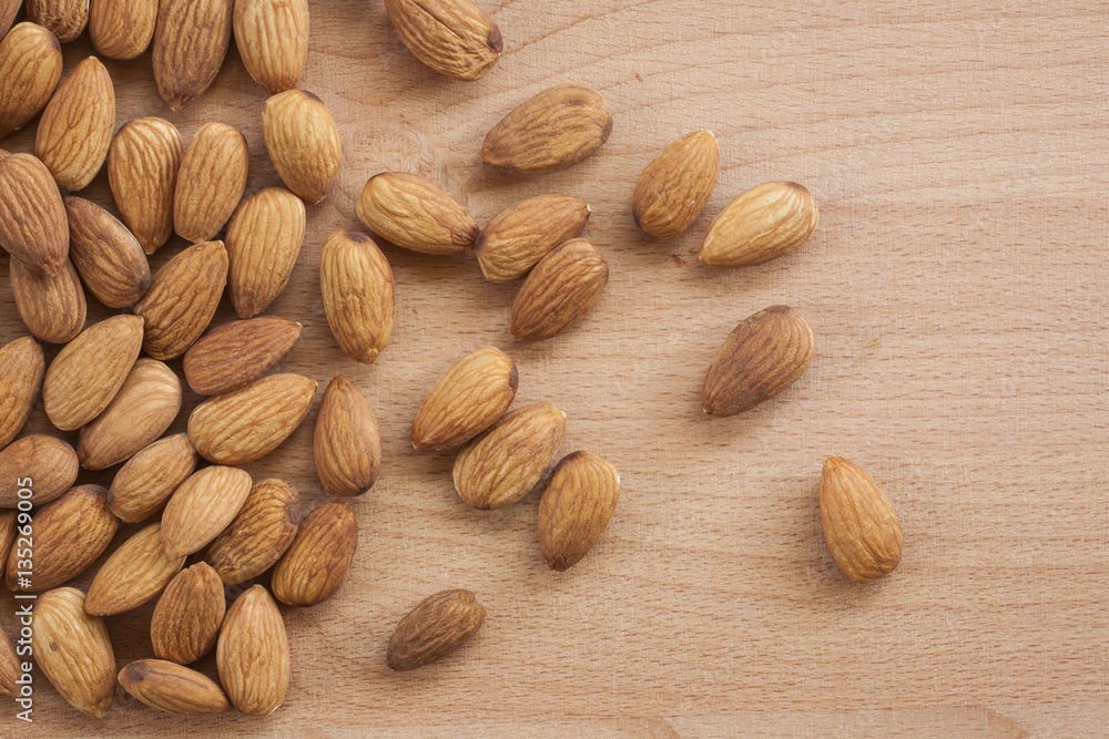 Almonds isolated on a white background, or on a plain wooden table. Almonds isolated on a white background, or on a plain wooden table.