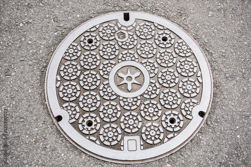 In the picture we can see a circular design of a classic art on a manhole cover. The art looks very neat and clean. It is made of steel and concrete. In the picture we can see a circular design of a classic art on a manhole cover. The art looks very neat and clean. It is made of steel and concrete.