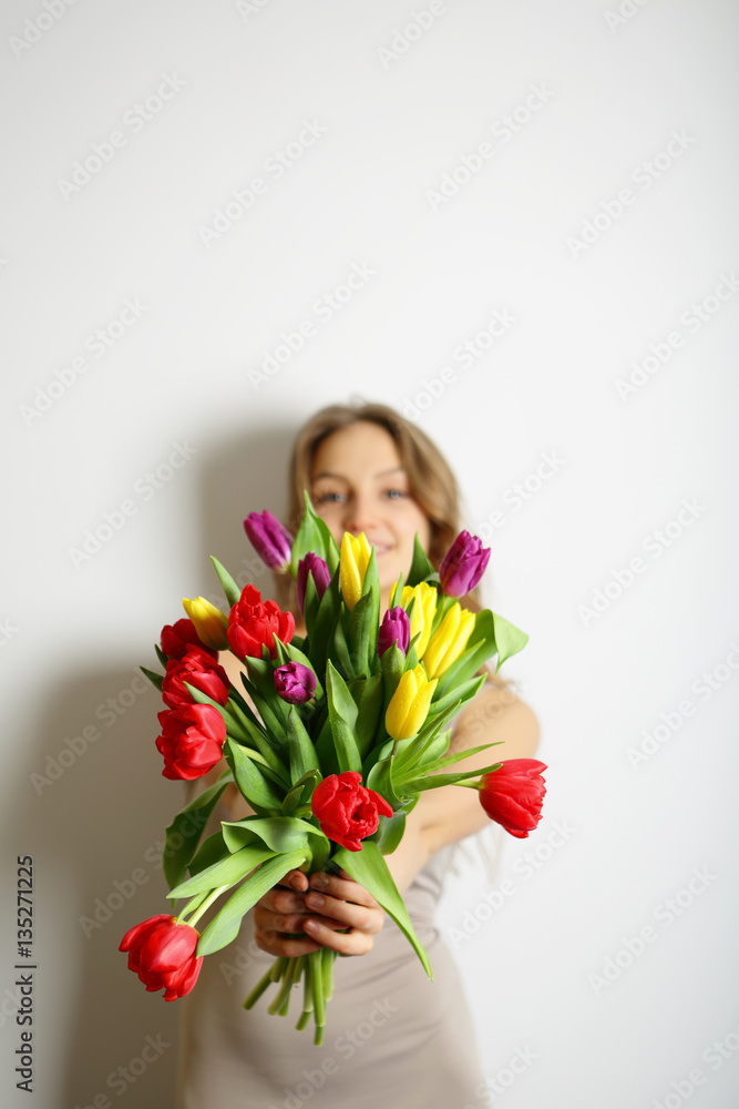 Girl gives a bouquet of colorful spring tulips