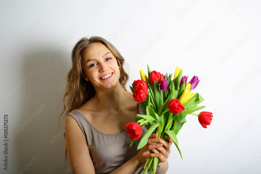 Young smiling woman with colorful flowers in hand Young smiling woman with colorful flowers in hand