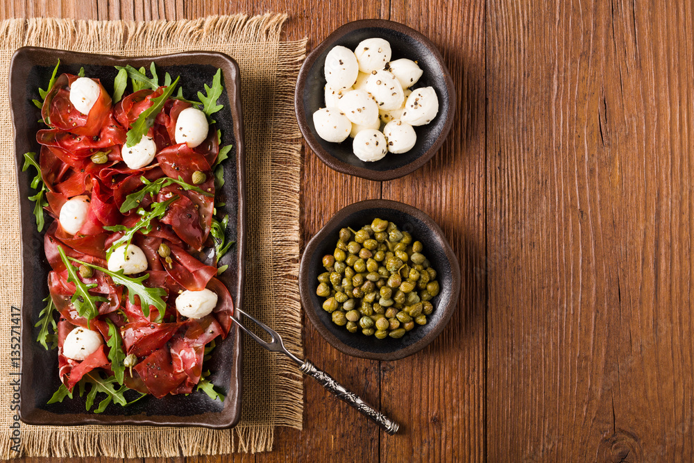 Beef carpaccio served with balls of mozzarella cheese, arugula a Beef carpaccio served with balls of mozzarella cheese, arugula a