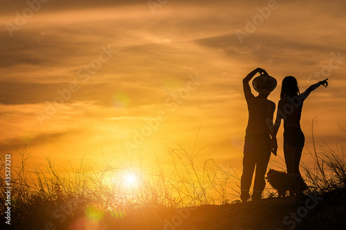 silhouette of couple in love on the beach at sunset. pointing to