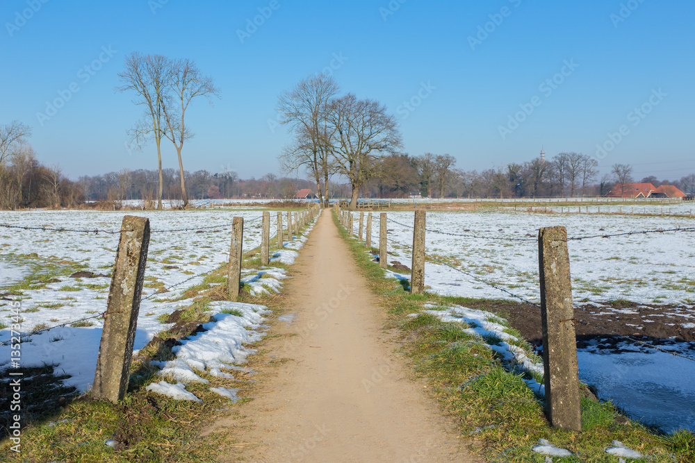 Naklejka premium Sandpath between snowy meadows in dutch winter