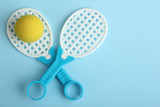 Toy racket with yellow ball on a blue background.