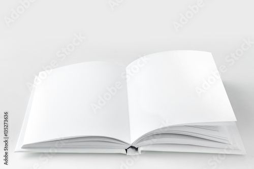 Open empty white book on a gray background.