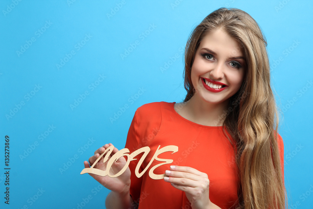 Beautiful girl holding LOVE letters on a blue background. Beautiful girl holding LOVE letters on a blue background.