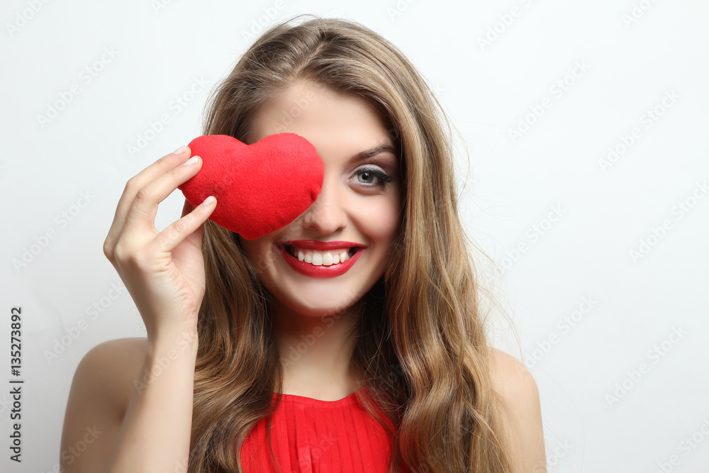Happy girl close one eye with red decorative heart. Happy girl close one eye with red decorative heart.