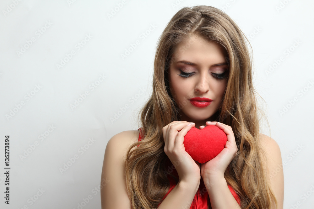 Beautiful girl posing with red decorative heart in hands. Beautiful girl posing with red decorative heart in hands.