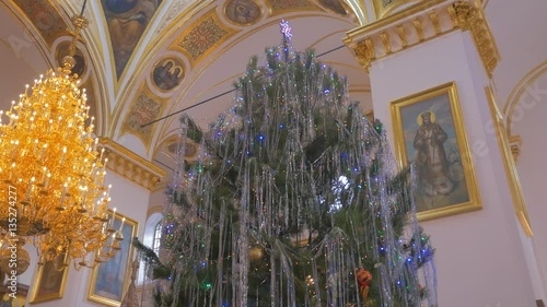 an Impressive Fir Tree and a Splendid Chadelier, Which Decorate an Old Orthodox Cathedral With High Dome Ceiling and Golden Looking Saint Images in Kiev photo