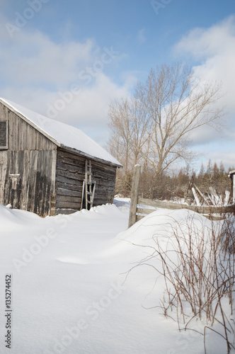 Old farm building on a sunny winter day with snow landscape
