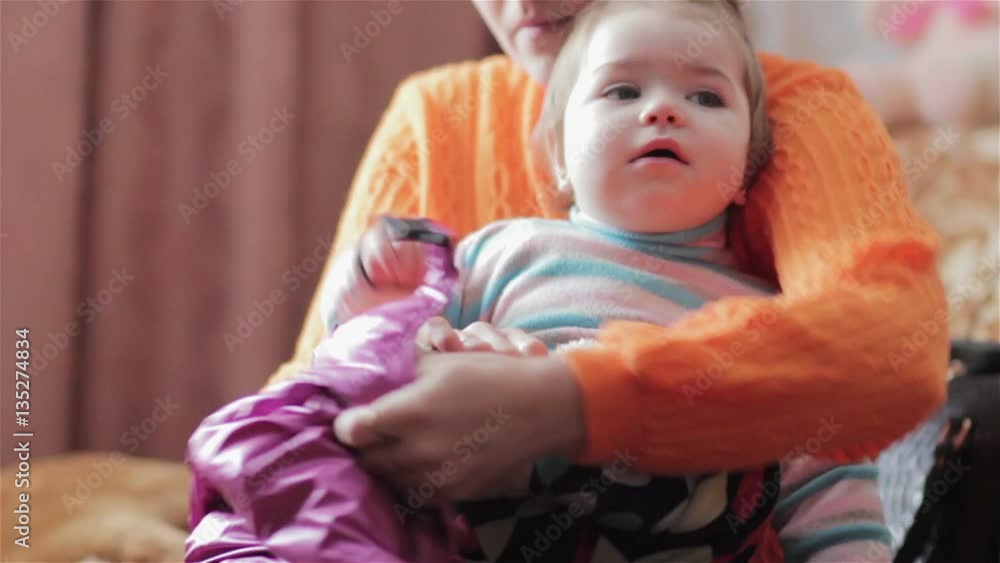 Mom Putting Little Baby Girl/mother holds daughter on her knees and puts on in warm clothes Mom Putting Little Baby Girl/mother holds daughter on her knees and puts on in warm clothes