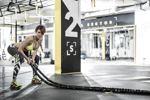Girl does exercise with fitness rope in gym
